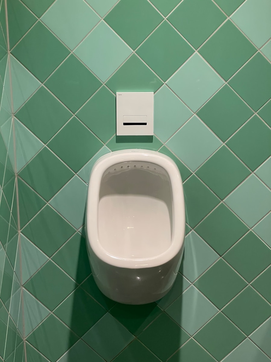 a urinal mounted on a green tiled wall