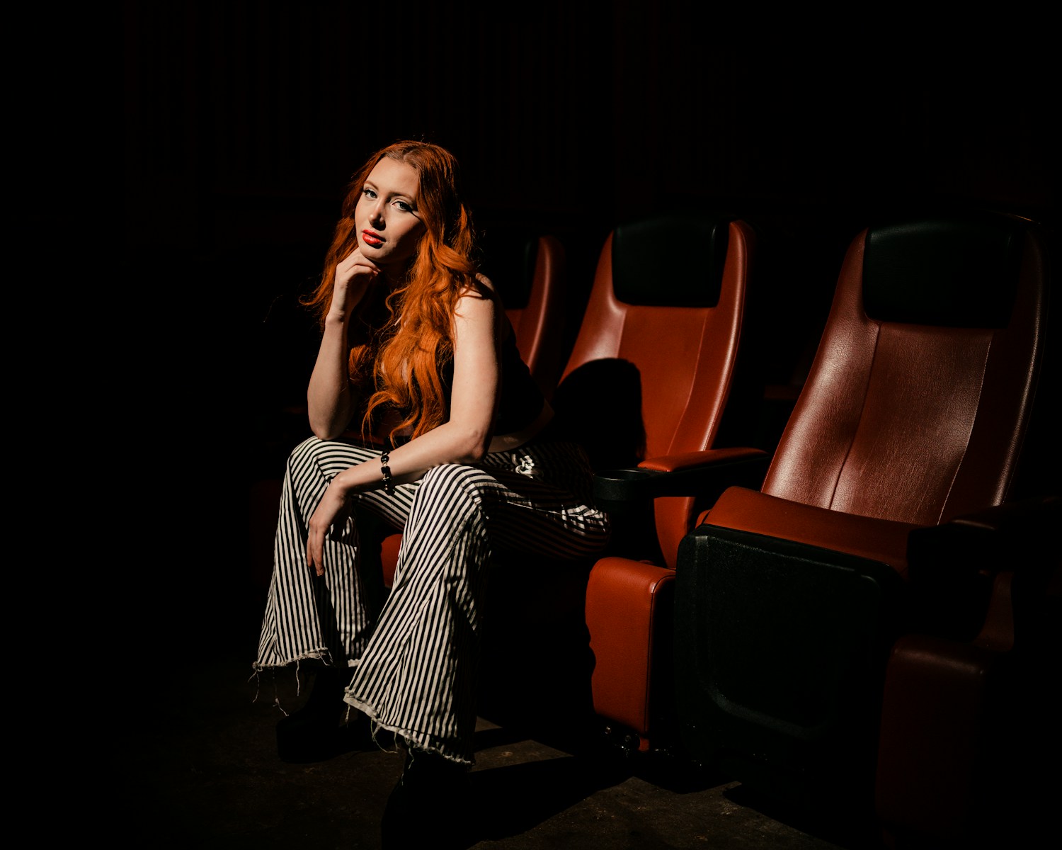 a woman with red hair sitting in a theater